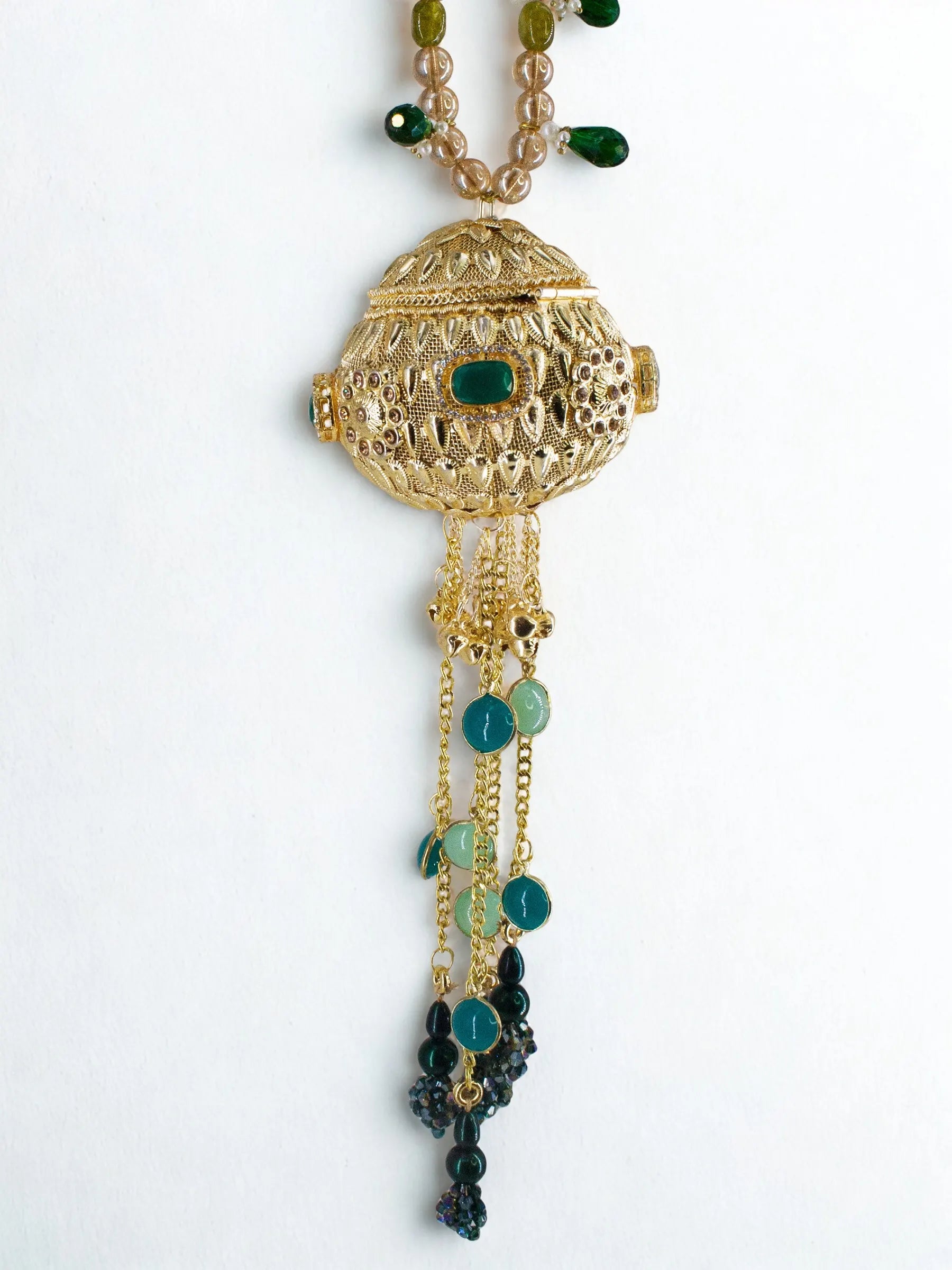 Gold orb potli bag with green gemstones and beaded chain handle on a white background