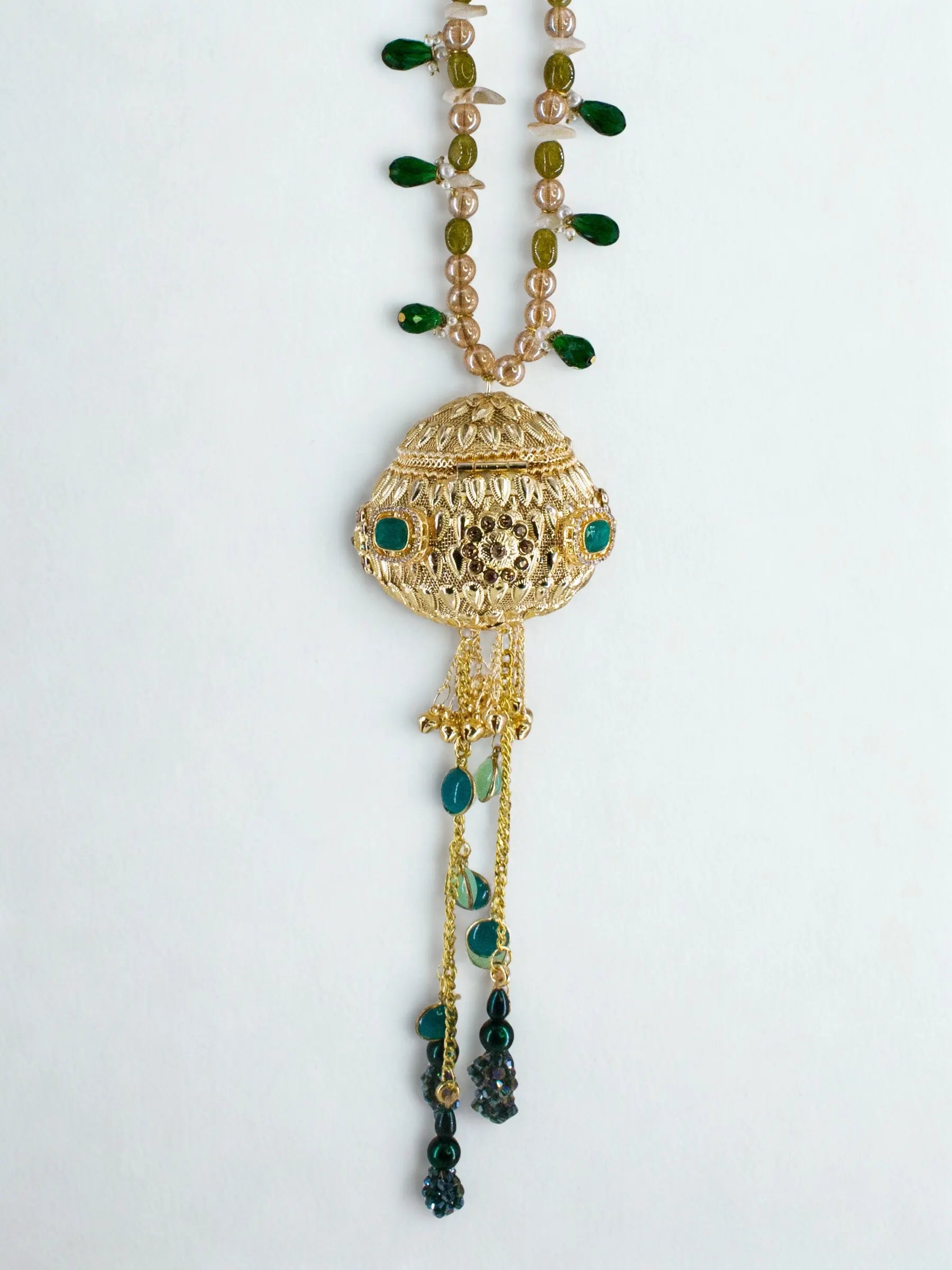 Gold orb potli bag with green gemstones and beaded chain handle on a white background, side view