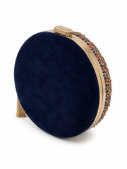 A round navy blue velvet clutch bag with a gold-tone metal frame, a beaded multicolor trim, and a gold tassel, shown on a white background.