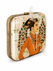Angled view of the Shahjahan Clutch showing the Mughal-style miniature portrait print, gem-encrusted floral spray details, textured metal frame, and feather-topped clasp.