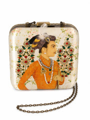 Front view of the Shahjahan Clutch on its antique gold chain strap, a square box clutch printed with a Mughal-style miniature portrait of a nobleman in an orange robe and jeweled turban, flanked by gem-encrusted floral sprays.