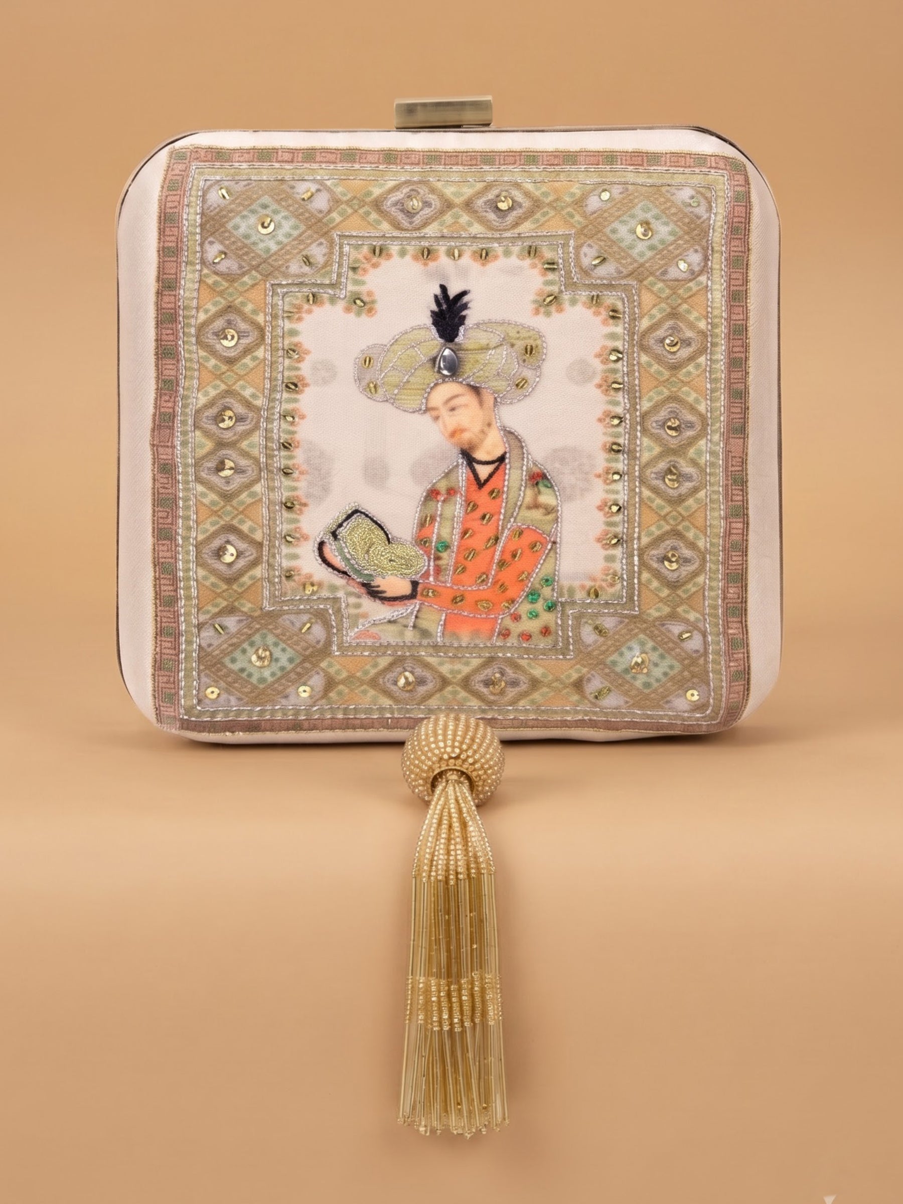 Sehzaada Embroidered Clutch, a square box clutch in ivory fabric with a Mughal-style miniature portrait of a young prince holding a book, framed by an embroidered geometric border and a beaded tassel.