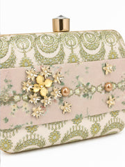 Close-up angled view of the Garden of Jewels Clasp Clutch showing the pink floral center band with detailed gold and pearl flower clusters and crystal accents, against the green paisley-patterned fabric side panels.