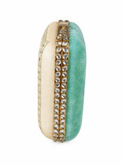 Side profile of the Saheliya Embroidered Clutch showing the cream gold-patterned panel and turquoise velvet panel divided by a row of crystal gemstones.